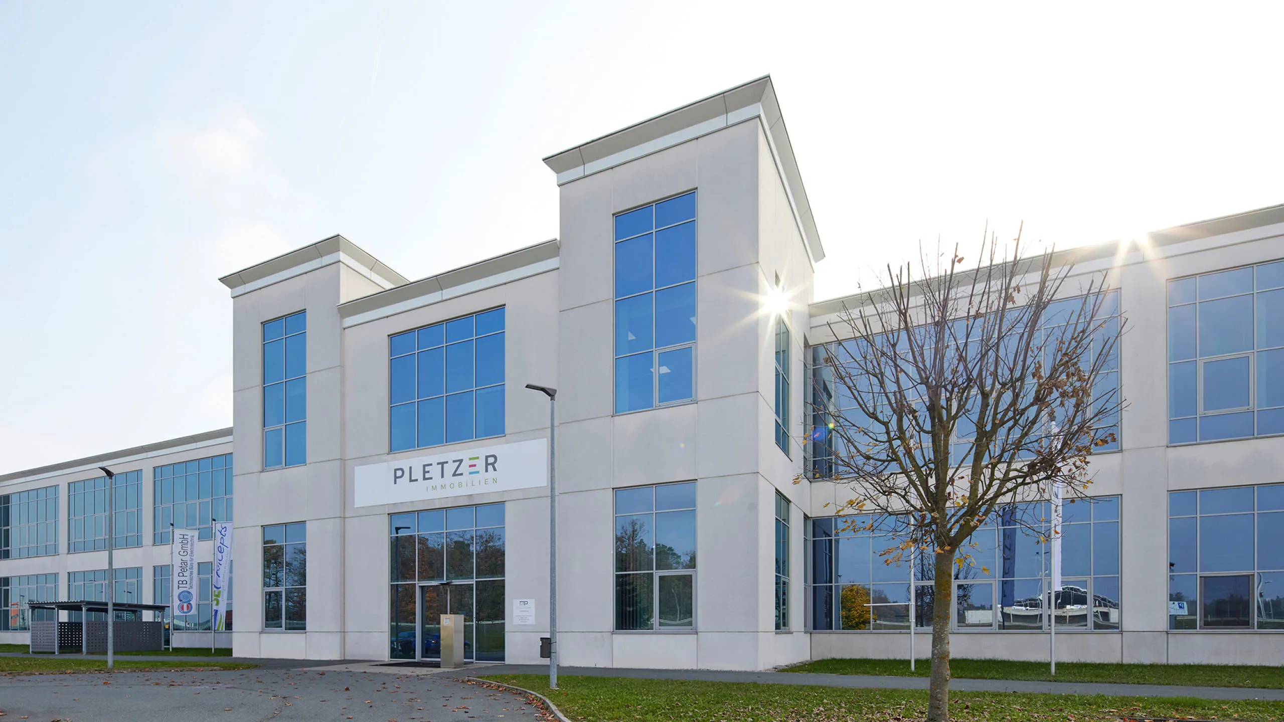 Gebäude von Pletzer Immobilien mit moderner Glasfassade und Logo über dem Eingangsbereich.